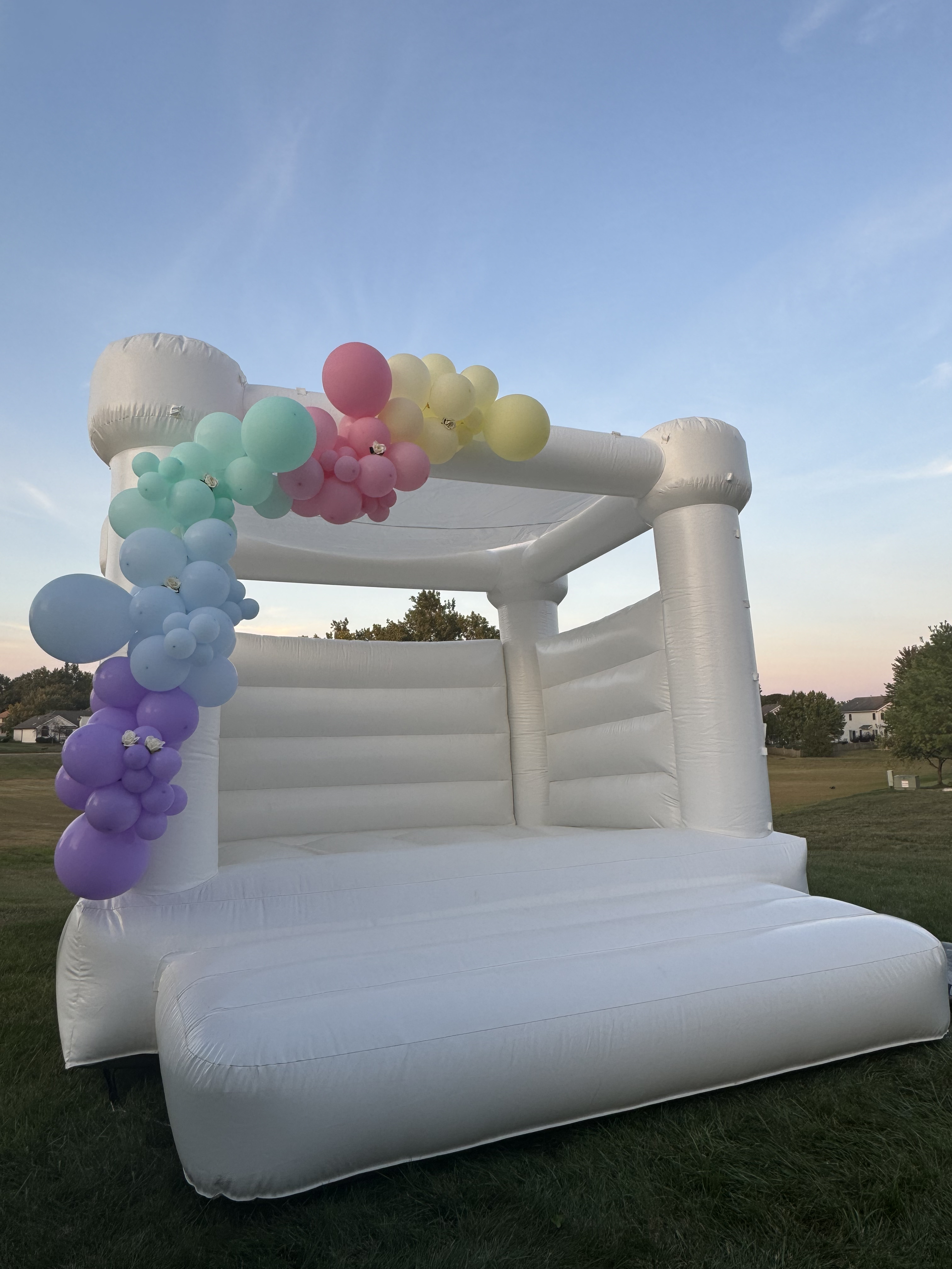 Pastel balloon styled white bounce house rental at golden hour in Fort Wayne Indiana