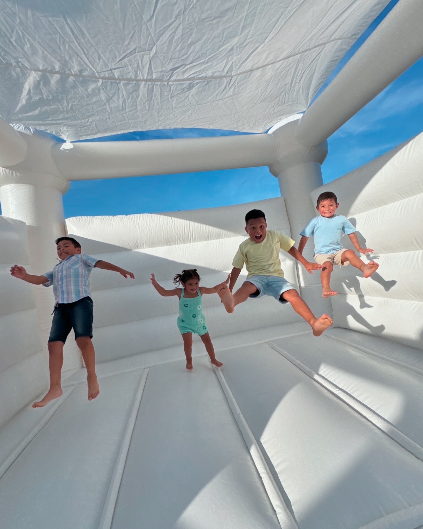 Kids jumping inside a white bounce house rental for a Fort Wayne party